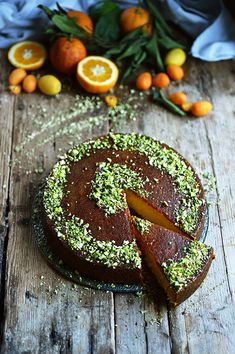 a chocolate cake with oranges and sprinkles around it on a wooden table