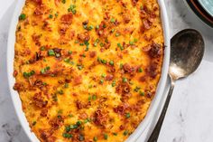 a casserole dish with meat, cheese and green onions in it on a marble surface