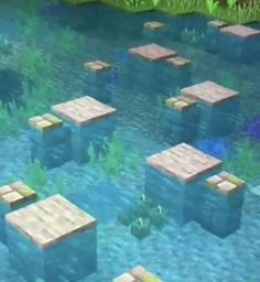 some blocks in the water with plants and grass around them on top of each other