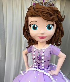 the doll is wearing a purple dress with pearls and a tiara on it's head