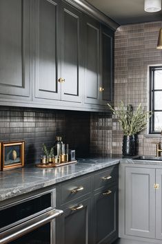 a kitchen with gray cabinets and marble counter tops, gold accents on the trimmings