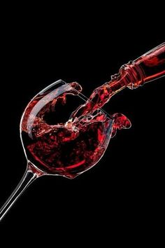 red wine being poured into a glass on a black background in the shape of a heart