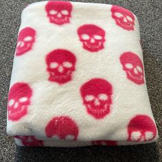 a red and white pillow with skulls on it sitting on the floor in front of a carpet