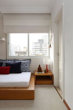 a bed room with a neatly made bed and a night stand next to a window