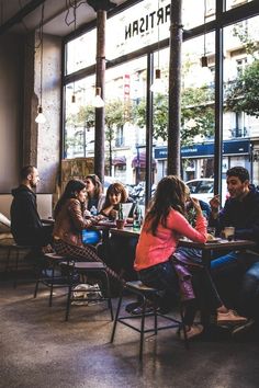 a group of people sitting at tables in front of a window with the word artisan written on it