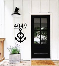 a door with a clock on it and an anchor in the middle is next to a potted plant