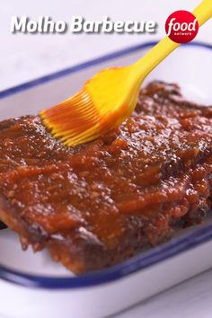 a yellow toothbrush is sticking out of some barbecue sauce in a square white dish