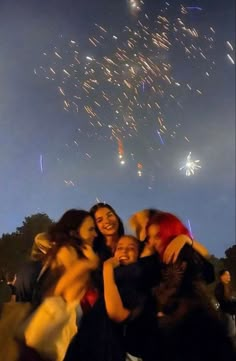 a group of people standing next to each other with fireworks in the sky