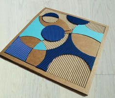 a piece of cardboard with blue and brown shapes on it sitting on top of a wooden table