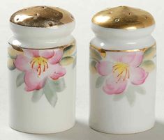 two salt and pepper shakers with pink flowers painted on the front, gold rimmed lids