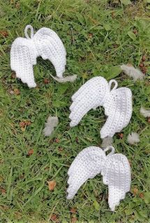 four knitted angel wings laying on the grass