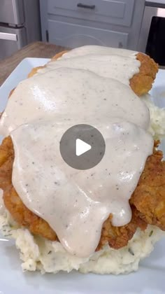 fried chicken covered in gravy on top of mashed potatoes