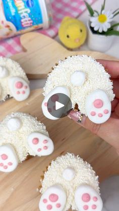 someone is decorating sheep cupcakes with white frosting and pink dots on them