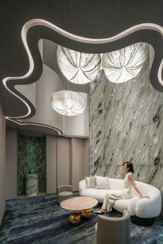 a woman sitting on a white couch in a room with marble walls and flooring