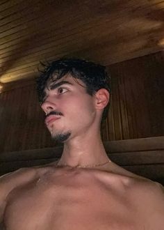 a man with no shirt standing in a sauna room looking up at the ceiling