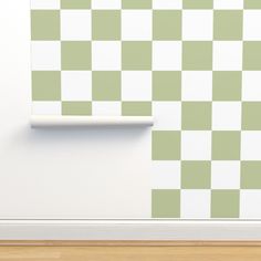 a green and white checkerboard wallpaper in an empty room with wood flooring