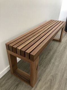 a wooden bench sitting on top of a hard wood floor next to a white wall