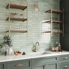 a kitchen with green cabinets and shelves filled with wine glasses, fruit and other items