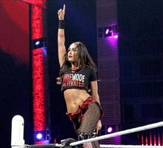 a woman standing on top of a wrestling ring with her hand up in the air