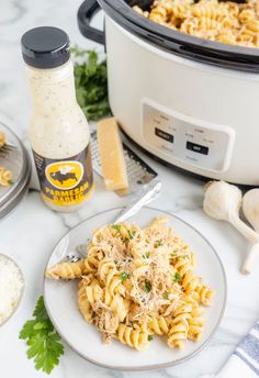 a plate of pasta with parmesan cheese and garlic next to an instant pressure cooker