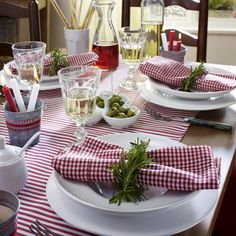 the table is set with red and white checkered placemats, plates, silverware, utensils and glasses