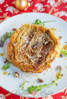 a white plate topped with food on top of a red and gold table cloth next to an ornament