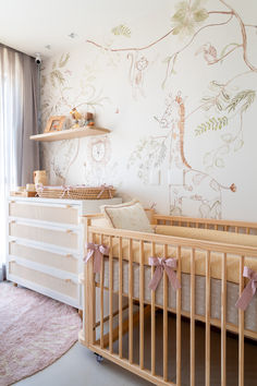 a baby's room with a crib, dresser and wallpaper in the background