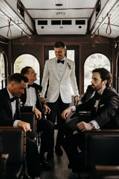 three men in tuxedos are sitting on a bus