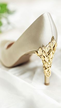 a pair of wedding shoes sitting on top of a white cloth covered tablecloth next to flowers