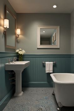 a white bath tub sitting next to a sink in a bathroom under a framed mirror