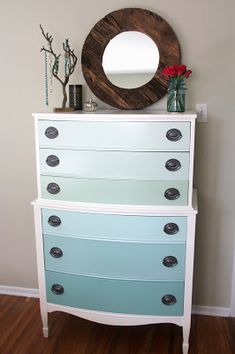 there is a white dresser with blue drawers and a mirror on the wall above it that says it's all about the ombre, rombie