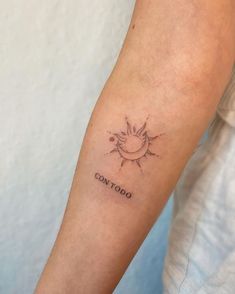 a woman's arm with a small sun tattoo on it