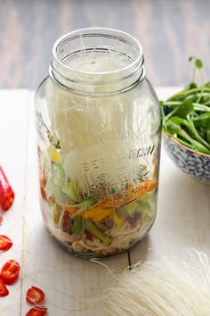 a glass jar filled with food sitting on top of a table next to a bowl