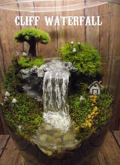 an aquarium with moss, rocks and water flowing from the top to the bottom in front of a wooden wall