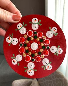 a hand holding a red paper plate with snowmen on it