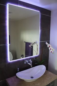 a bathroom with a sink, mirror and flowers on the counter top in front of it