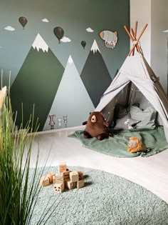 a child's bedroom with a teepee tent and mountains painted on the wall