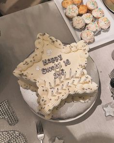 a star shaped cake sitting on top of a table next to cupcakes and silverware