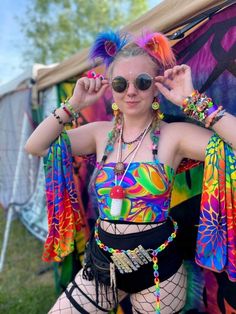 a woman with colorful hair and sunglasses standing in front of a tent