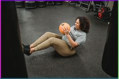 a woman sitting on the ground holding an orange ball