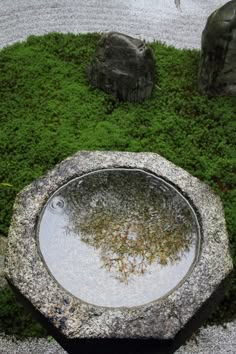 a stone fountain surrounded by moss and rocks