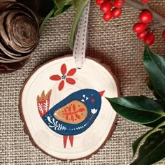 a wooden ornament with an image of a bird on it next to some red berries