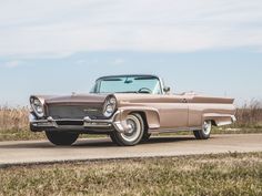 an old car is parked on the side of the road in front of some grass