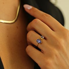 a woman's hand with a gold ring and two blue stones on her finger