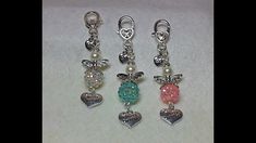 three charms are sitting on a white surface with beads and hearts hanging from the clasps