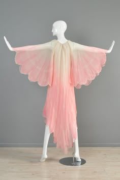 a mannequin wearing a pink and white dress with wings on it's back