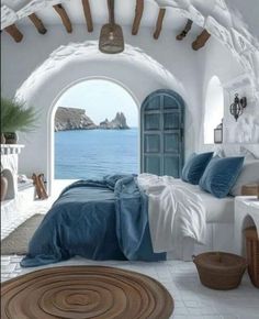 a bedroom with an arched doorway leading to the ocean and a bed that has blue sheets on it