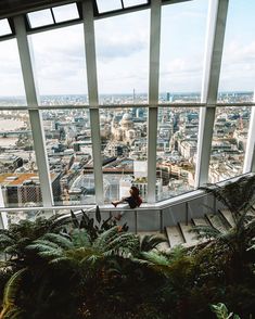 a woman sitting on top of a building looking out at the city from an observation platform