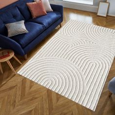 a living room with a blue couch and white rug on top of the wooden floor