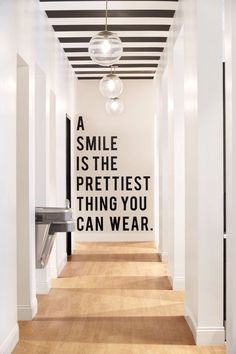 a hallway with black and white wallpaper that says, a smile is the prettiest thing you can wear